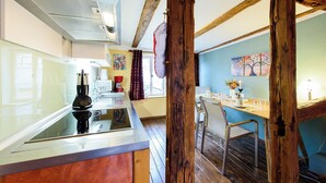 A kitchen with a modern stove, a coffee maker, and a dining area with a table and chairs. - "Sunshine" in harmony and color (Quedlinburg)