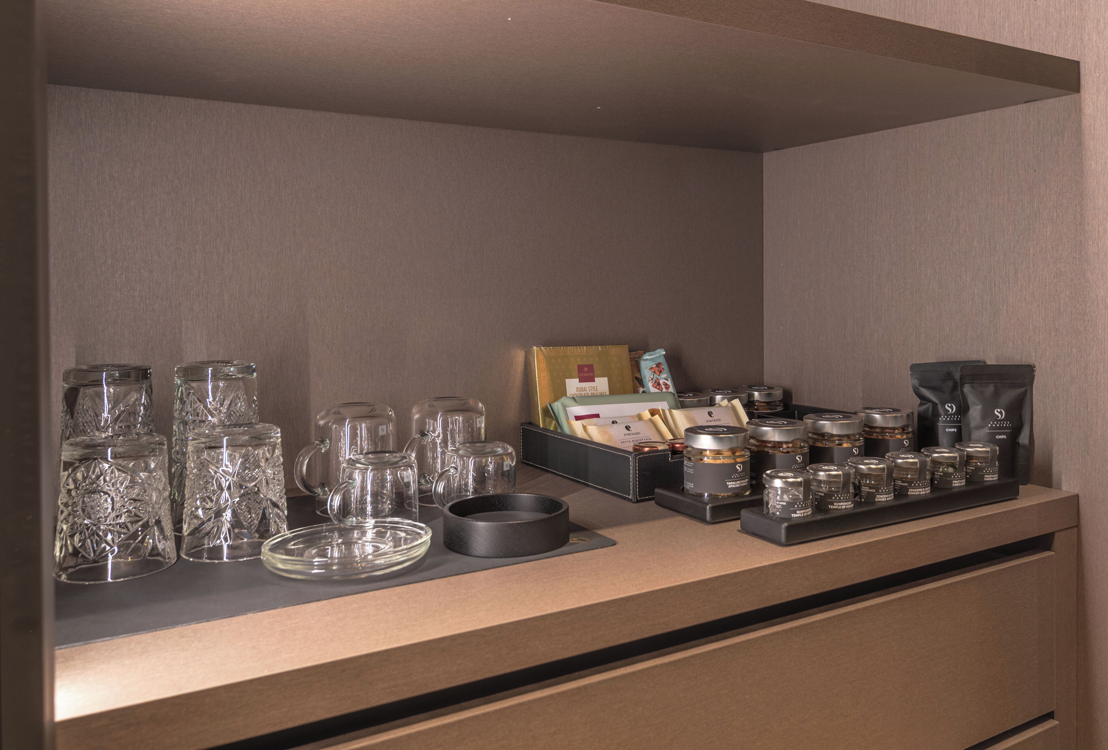 Una zona de bar con cristalería, una máquina de café y condimentos.