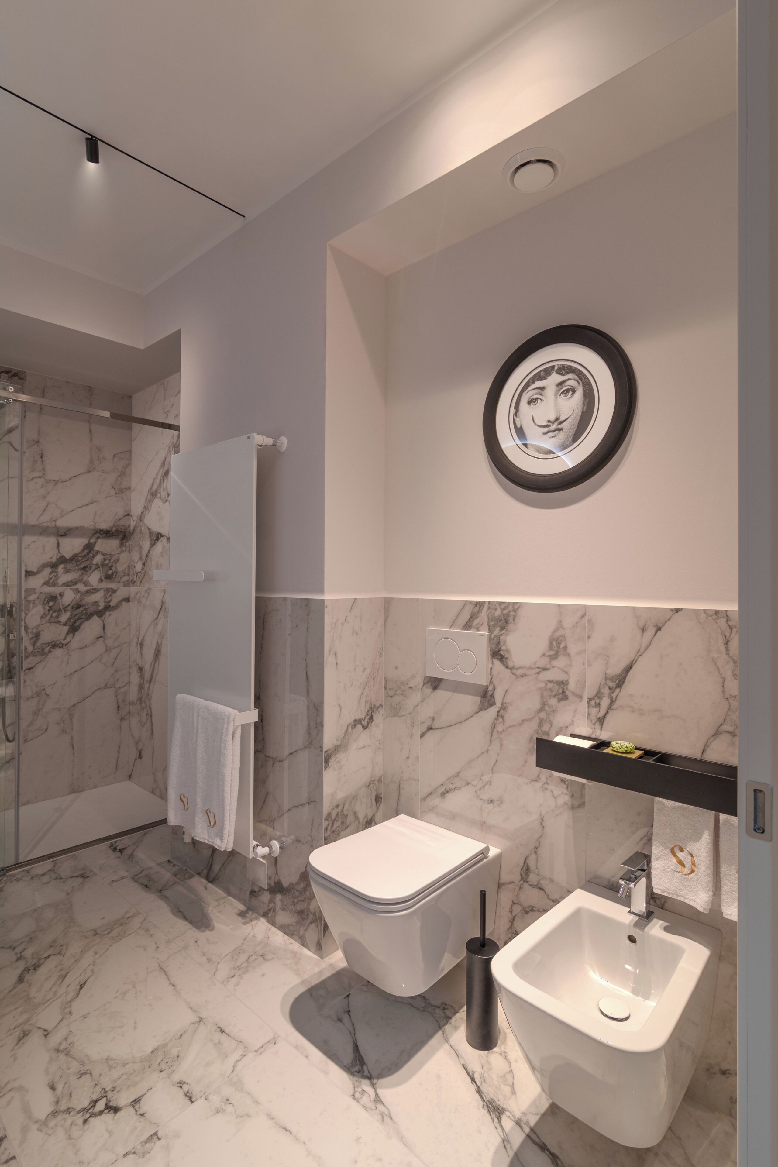 Une salle de bain moderne avec un sol en marbre, des toilettes, un bidet et une douche à parois de verre.