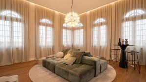 A modern living room with a large sofa, a round coffee table, and a chandelier. - Residenza Palazzo Poste (Verona)