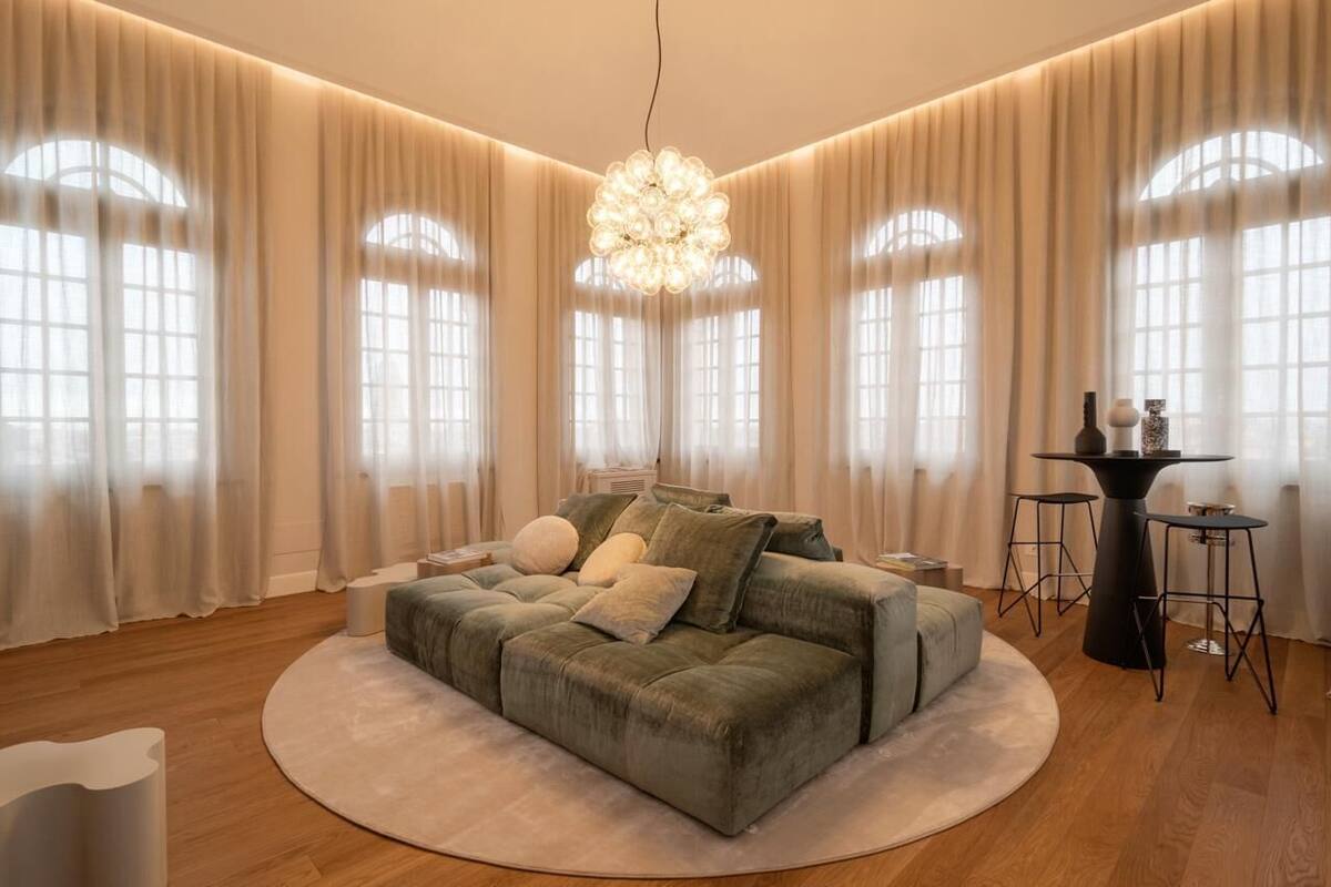 A modern living room with a large sofa, a round coffee table, and a chandelier.