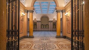 A grand hallway with ornate columns, a patterned floor, and a skylight. - Residenza Palazzo Poste (Verona)