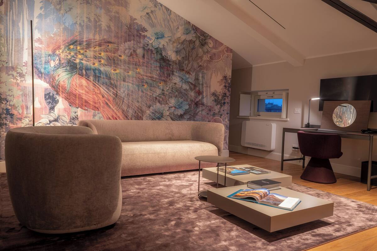 A modern living room with a sofa, a coffee table with magazines, a decorative wall, a TV, and a desk with a chair.