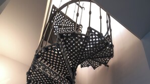 A spiral staircase with intricate metal railings and a wooden floor. - Residenza Palazzo Poste (Verona)