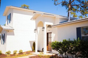 Un edificio blanco de dos pisos con una puerta marrón, un pequeño porche y un buzón.
