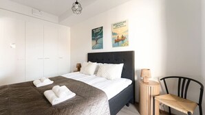 A bedroom with a bed, a chair, a nightstand, and two posters on the wall.