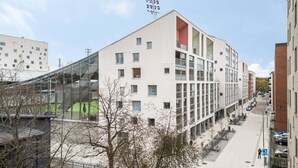 A modern building with a glass facade, multiple floors, and a flat roof. - Superior family room for 5 guests - Private Sauna (Tampere)