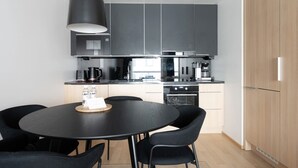 A modern kitchen with dark cabinets, a black dining table, and chairs. - Superior family room for 5 guests - Private Sauna (Tampere)