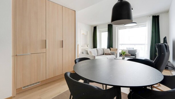 A modern living room with a round table, black chairs, a sofa, and a large window with curtains. - Superior family room for 5 guests - Private Sauna (Tampere)