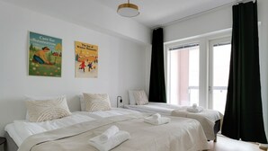 A hotel room with two beds, a large window with black curtains, and two wall posters. - Superior family room for 5 guests - Private Sauna (Tampere)