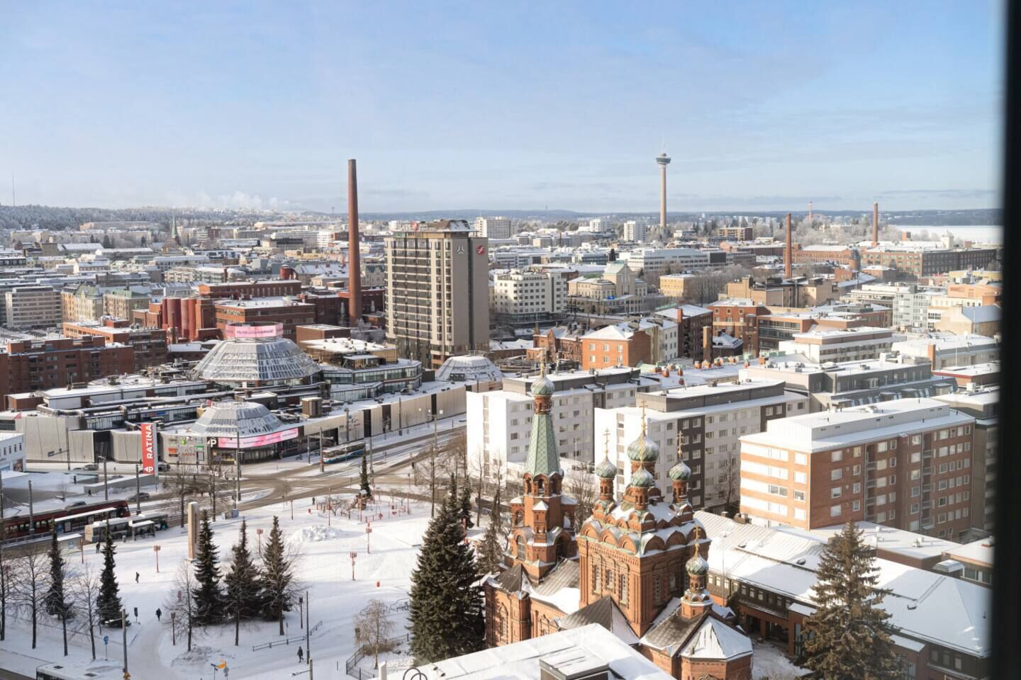 A cityscape with a mix of modern and historical buildings, including a prominent church with domes and a tall tower.