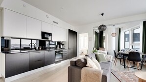 A modern kitchen with a central island, a dining area with a table and chairs, and a living room with a sofa. - Nokia Arena By Come in! Deluxe Family Room (Tampere)