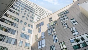 A multi-story building with a modern architectural design, featuring numerous windows and a clean, geometric facade. - Arena Comfort Queen-Free Gym-Views (Tampere)