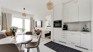 Ett modernt kök med vita skåp, en inbyggd ugn och en kaffebryggare.