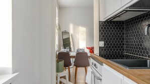 A narrow kitchen with a wooden countertop, a stove, and a dining area with chairs and a table. - Cozy & Stylish Downtown Studio for Four guests (Tampere)
