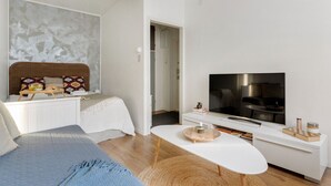 A modern living room with a bed, a TV, and a dining area. - Cozy & Stylish Downtown Studio for Four guests (Tampere)