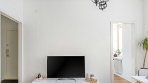 A modern living room with a flat-screen TV on a white console, a small chess set, and a potted plant. - Cozy & Stylish Downtown Studio for Four guests (Tampere)