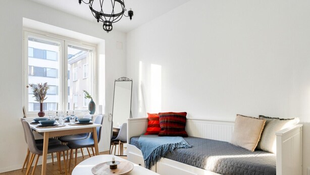 A compact living space with a dining table, a sofa, and a small table with a candle. - Cozy & Stylish Downtown Studio for Four guests (Tampere)