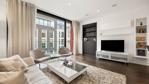 Un salon moderne comprenant un canapé, des fauteuils, une table basse, un téléviseur et une cheminée.