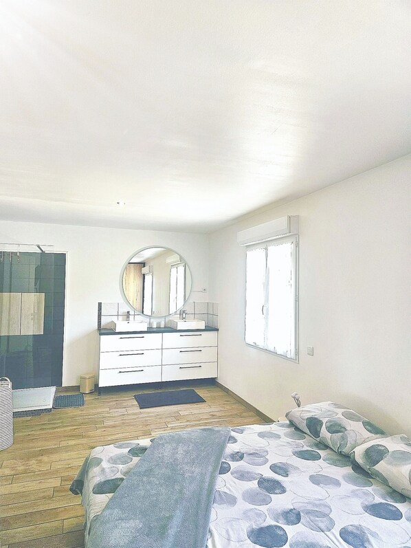 A bedroom with a bed, a dresser, a mirror, and a window.