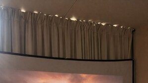 A projection of a couple holding hands on a beach at sunset, a bed, and curtains. - Mirror House & Forest Sauna Retreat (Březová)