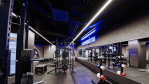 A gym with weightlifting equipment, a mirrored wall, and a 'STRENGTH' sign.