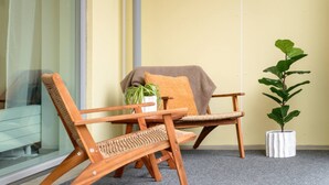 A room with a wooden chair, a cushioned chair, a small potted plant, and a window with a view.