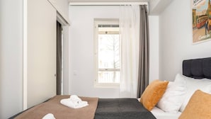 A hotel room with a bed, a window, and a view of buildings outside.