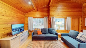 A wooden cabin interior with a sofa, TV, and a lamp. - Tormore - wooden log cabin in the Cairngorms (Carrbridge)