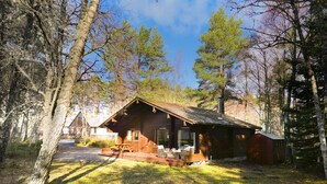 A cabin with a porch, a chimney, and a deck. - Tormore - wooden log cabin in the Cairngorms (Carrbridge)