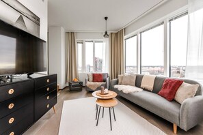 A modern living room with a sofa, TV, and a view of the city.