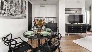 A modern dining area with a round table, black chairs, and a vase of flowers.