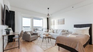 Una habitación de hotel moderna con cama, sofá, escritorio y zona de comedor.