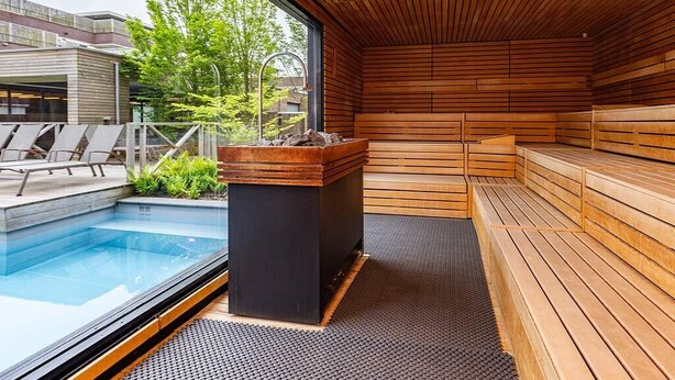 Una sauna moderna con bancos de madera, una pequeña piscina y vistas al exterior.