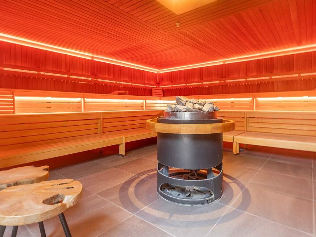 Eine Sauna mit Holzbänken und einem Feuerkorb in der Mitte.