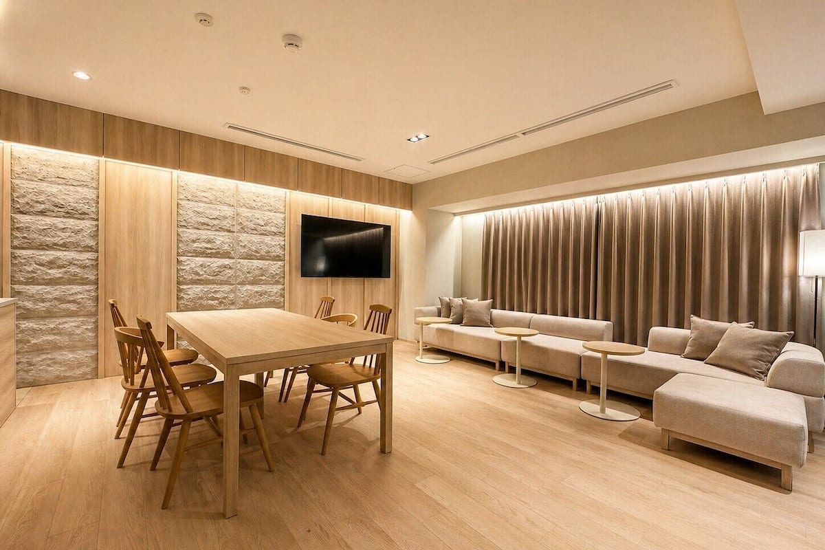 A modern living room with a wooden dining table, sofa, and TV mounted on the wall.