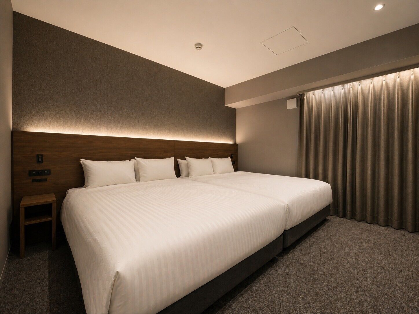Ein modernes Hotelzimmer mit einem großen Bett, einem Nachttisch, einer Kopfteil und einem Fenster mit Vorhängen.