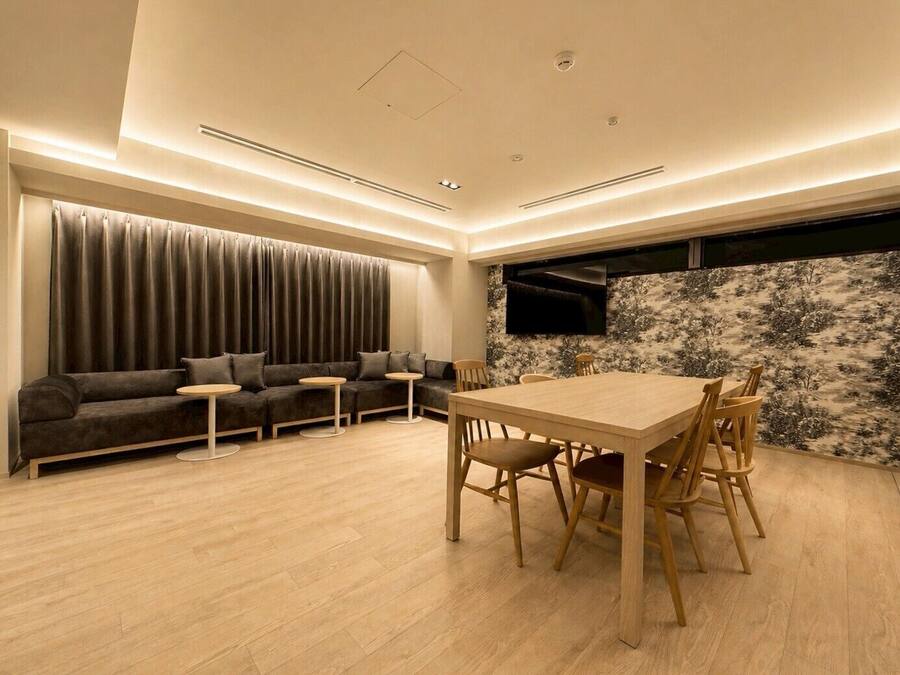 A modern living room with a sofa, a dining table, and a TV mounted on the wall.