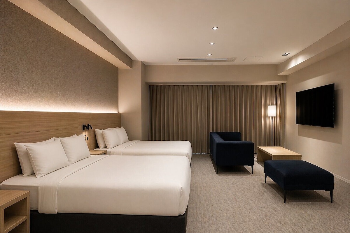 A hotel room with two beds, a desk, a chair, a TV, and a large window with curtains.