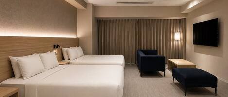 A hotel room with two beds, a desk, a chair, a TV, and a large window with curtains.