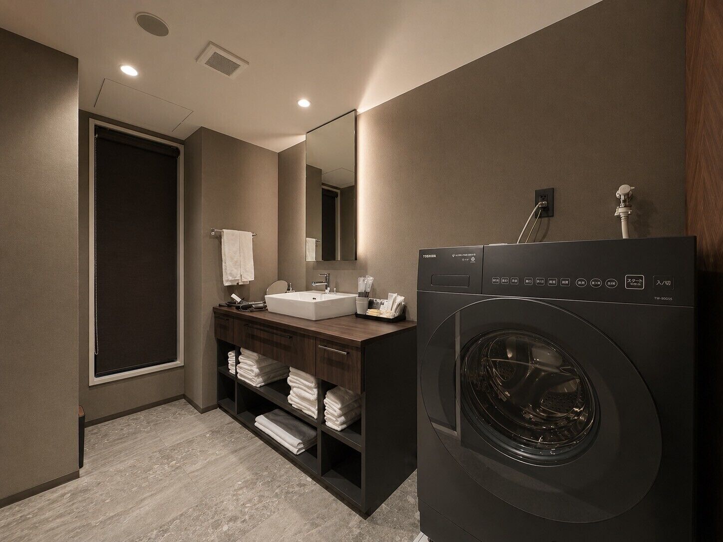 A modern bathroom with a built-in washer and dryer, a vanity with a mirror, and a towel rack.