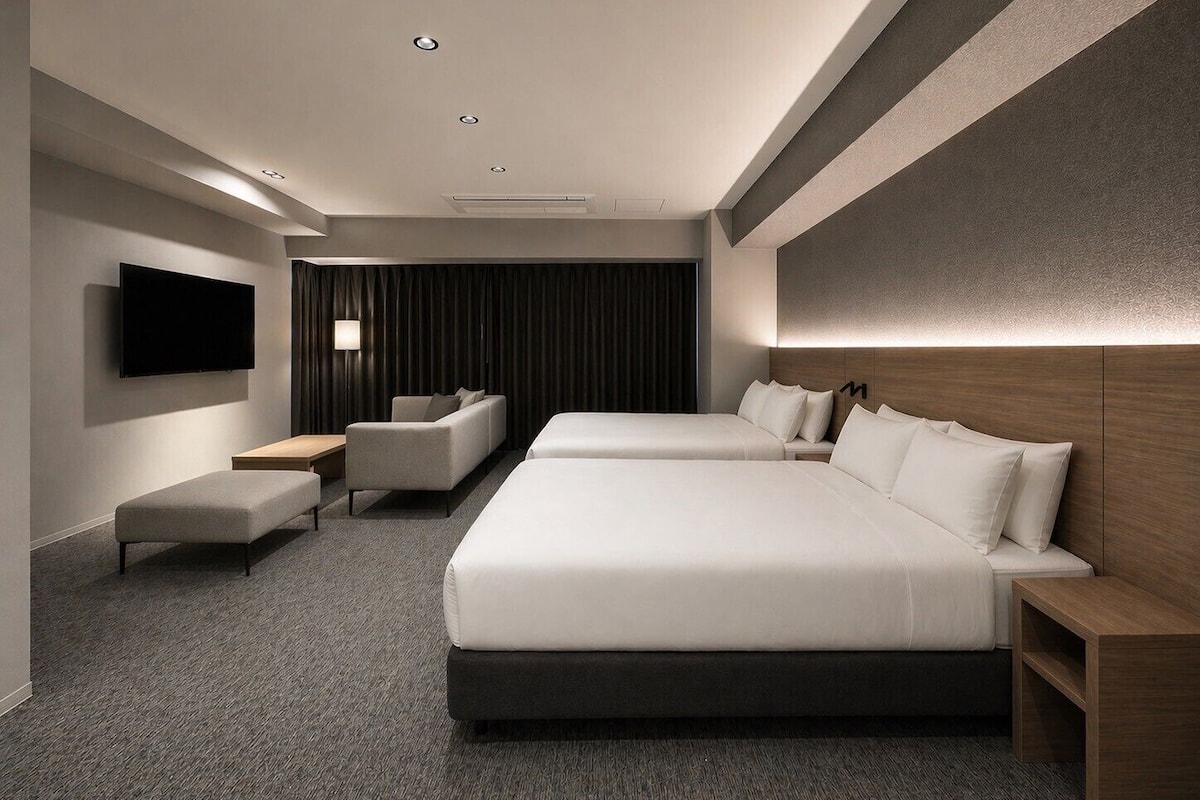 A modern hotel room with a large bed, a sofa, a TV, and a desk.