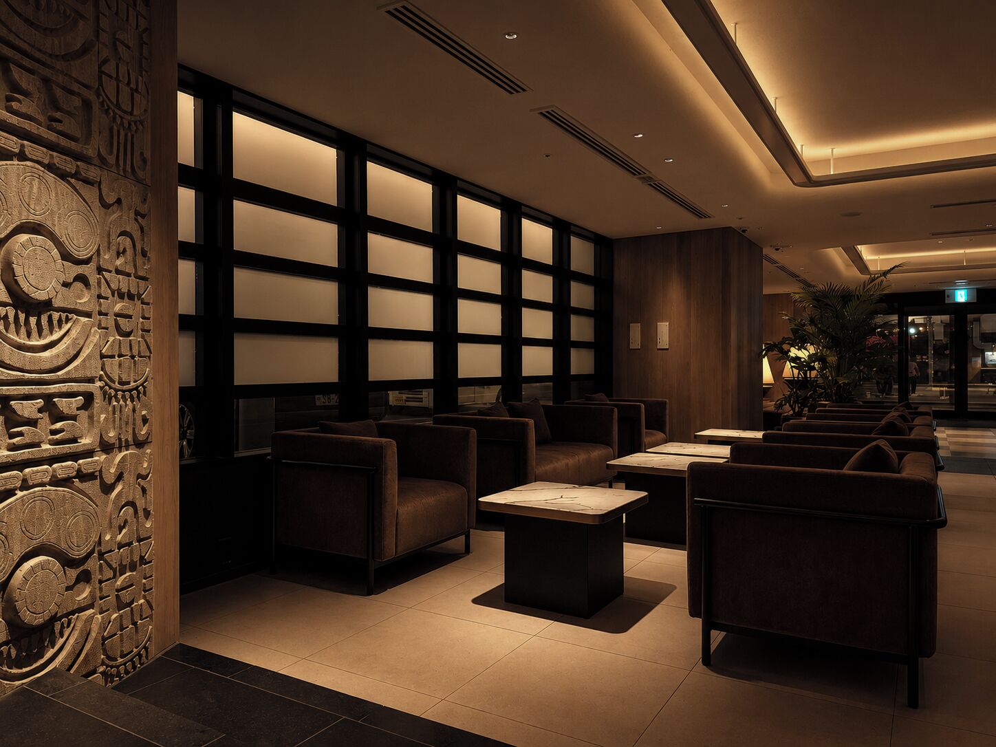 A modern lobby with seating, a decorative wall, and a large window.
