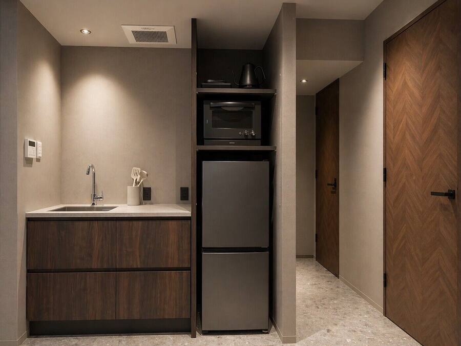 A compact kitchen with a built-in microwave, a refrigerator, and a sink with a utensil holder.