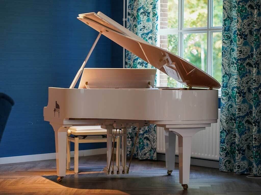 A grand piano in a room with a blue wall and patterned curtains.