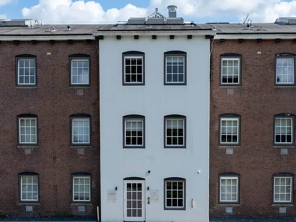 A multi-story building with a central white facade, multiple windows, and a flat roof.