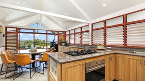 Een moderne keuken met een gasfornuis, houten keukenkastjes en een groot raam met uitzicht op een schilderachtig landschap.
