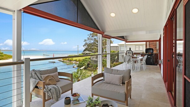 Een balkon met uitzicht op het strand, een barbecue en een eethoek.