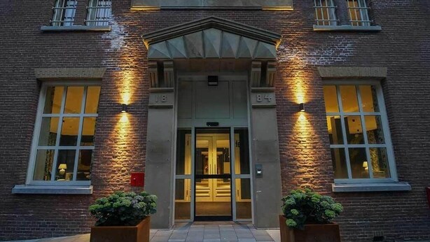 A brick building with a sign reading 'SCHUTTERSWEI' and a double door entrance. - Memorable Stay in Former Prison Building (Alkmaar)