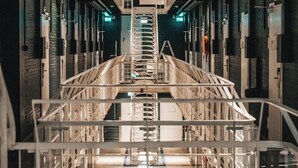 A corridor with a central staircase, metal railings, and a series of doors on either side. - Memorable Stay in Former Prison Building (Alkmaar)